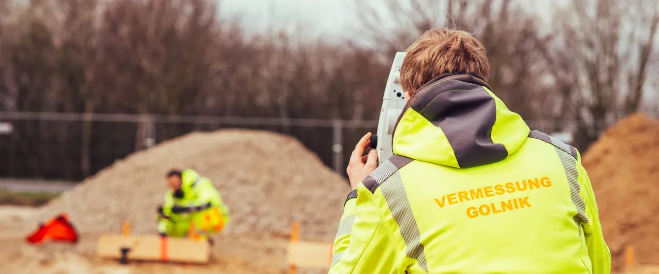 Vermessungstechniker von GOLNIK & PARTNER steckt auf einer Baustelle mit dem Tachymeter ein Gebäude ab