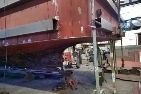 Steel hull of a ship on blocks in a shipyard hall