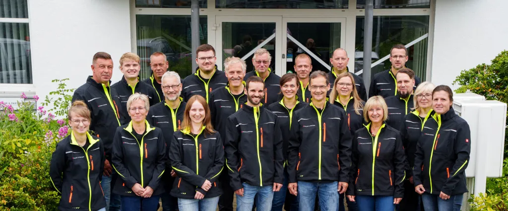 Das Team von GOLNIK & PARTNER in Arbeitsjacken vor dem Bürogebäude in Rostock